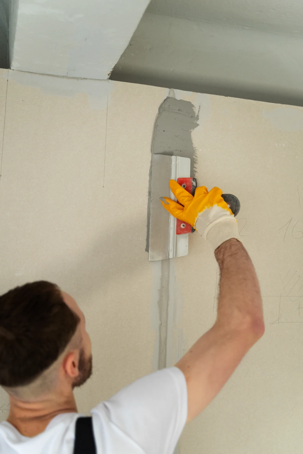 construction worker doing drywall repair using mud and trough.